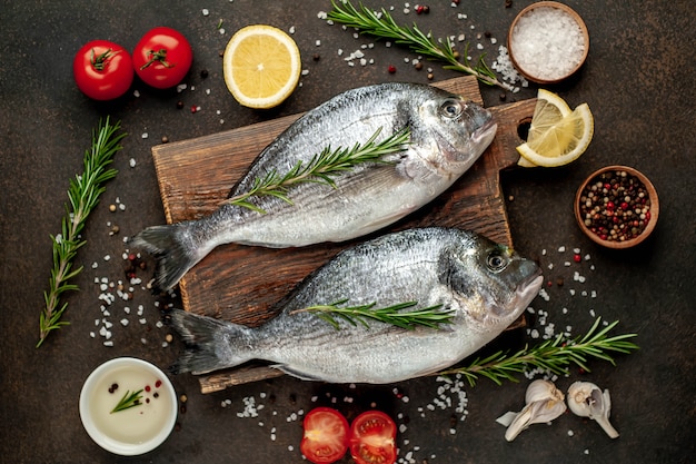 Raw dorado fish with spices and ingredients tomato, razmorin, sunflower oil, lemon on a stone background