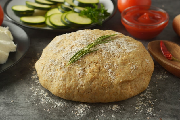 Raw dough and fresh ingredients for vegan pizza.