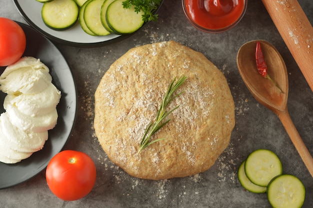 Raw dough and fresh ingredients for vegan pizza.