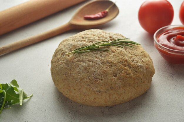 Raw dough and fresh ingredients for vegan pizza.