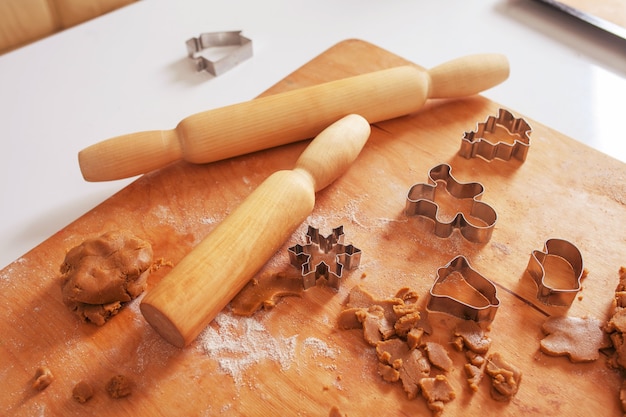 Pasta cruda e mattarelli per i biscotti di natale. tagliabiscotti - albero di natale, fiocco di neve, campanellino, omino di pan di zenzero. cottura di natale. preparazione per le vacanze, natale, capodanno.