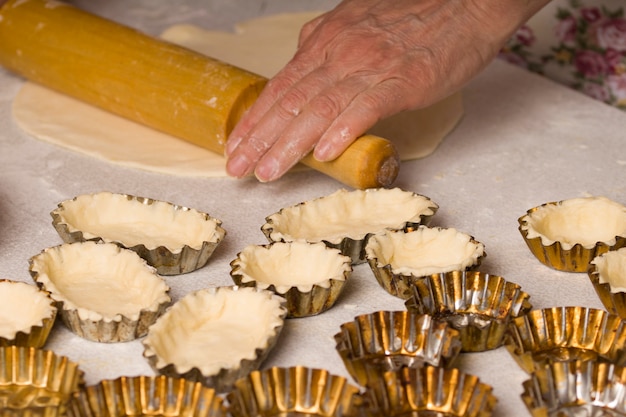 Raw dough in tartlet tins on baking tray.