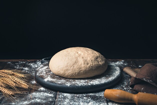 Raw dough and wheat spikelets on a black background.