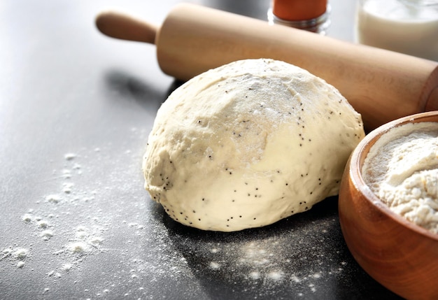 Raw dough with flour and rolling pin on table