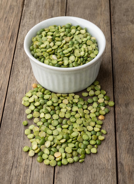 raw dried green peas in a bowl over wooden table.