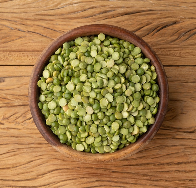 raw dried green peas in a bowl over wooden table.