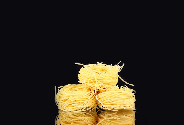 Raw dry nest pasta with reflection on black