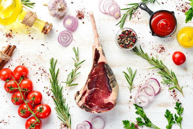 Raw dry steak on bone Tomahawk steak on a white wooden background Top view Free space for your text