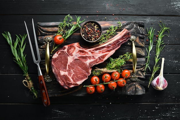 Raw dry steak cowboy on black background Tomahawk steak BBQ Top view Free space for text