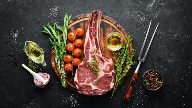 Raw dry steak tomahawk on a black background Steak Cowboy Barbecue Top view Free space for text