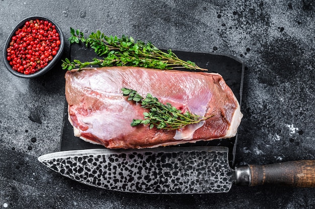 Raw duck breast fillet on a marble board. Black background. Top view.