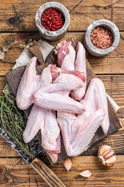 Raw duck or chicken wings on a butcher board Dark wooden background Top view