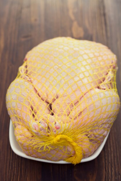 Raw duck on dish on brown wooden surface