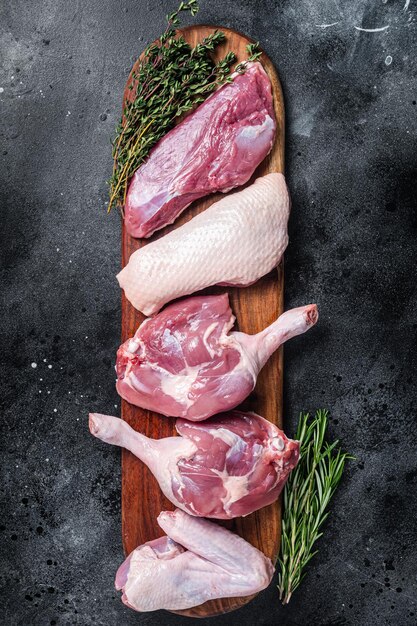 Raw duck meat ready to cook breast fillet legs wings Black background Top view