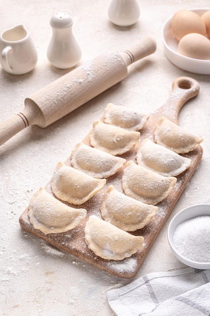 Raw dumpling with potatoes Preparation dumplings on a light background on a wooden board Fresh handmade Ukrainian dumplings National traditions masna Homemade dough products craft cooking