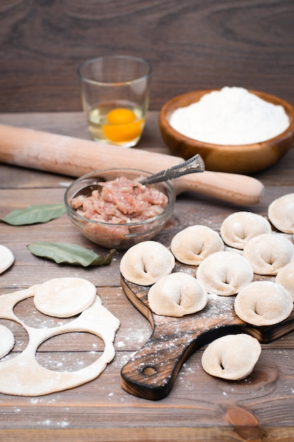 Raw dumplings on a cutting board and ingredients for their preparation