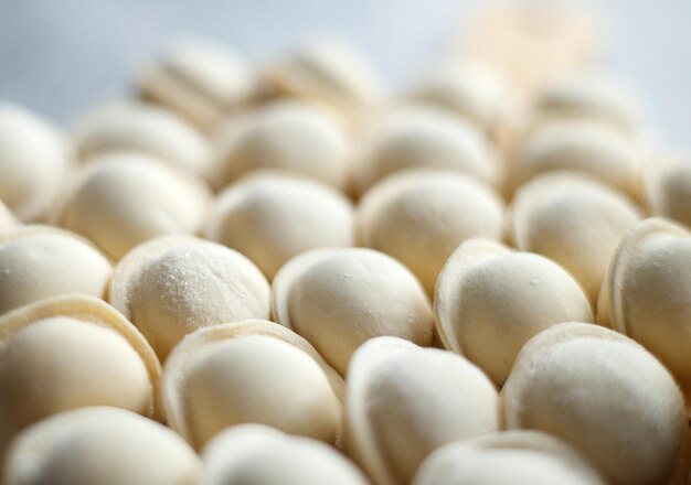 Raw dumplings lie in a row on a gray background