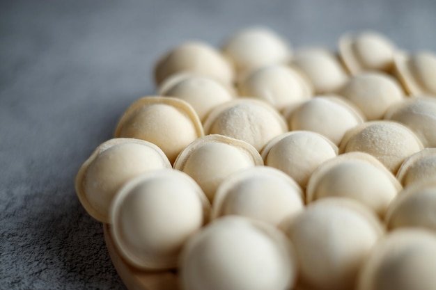 Raw dumplings lie in a row on a gray background