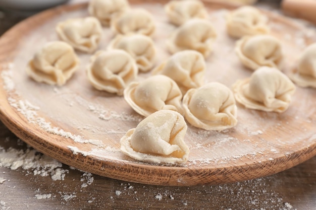 Raw dumplings on wooden board closeup