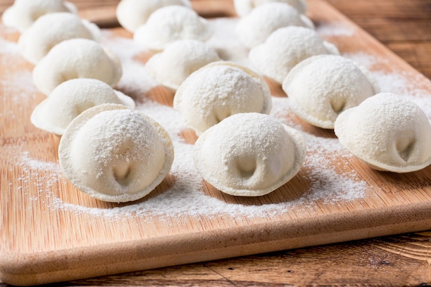 Raw dumplings on a wooden chopping Board in the kitchen.