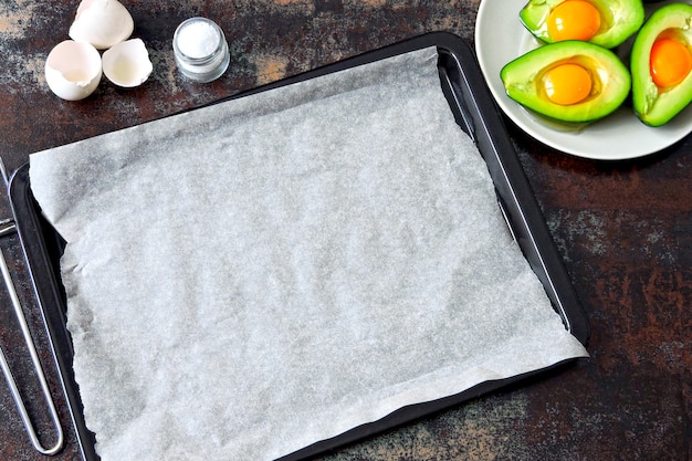 Raw egg in avocado on a baking sheet. Cooking avocado with egg. Keto lunch recipe.