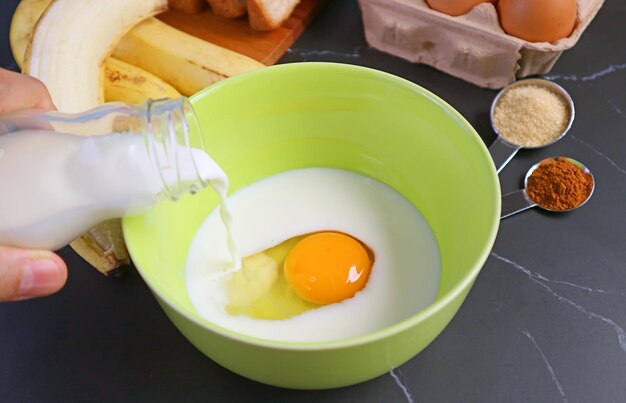 Raw Egg in Mixing Bowl Being Poured by Fresh Milk for Baking Banana Bread Pudding