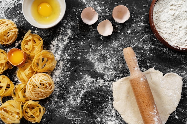 raw egg pasta with flour on black background