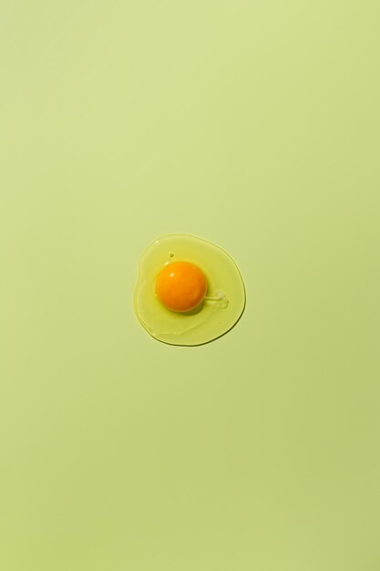 Photo raw egg yolk on a green background view from above