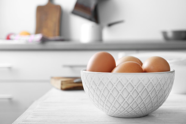 Raw eggs in bowl on kitchen table