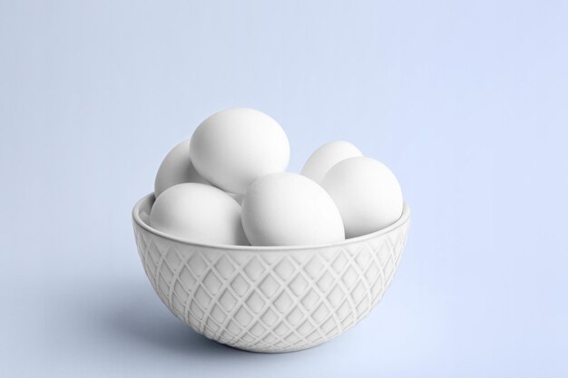 Raw eggs in bowl on white background