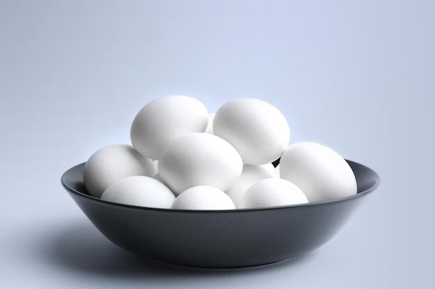Raw eggs in bowl on white background