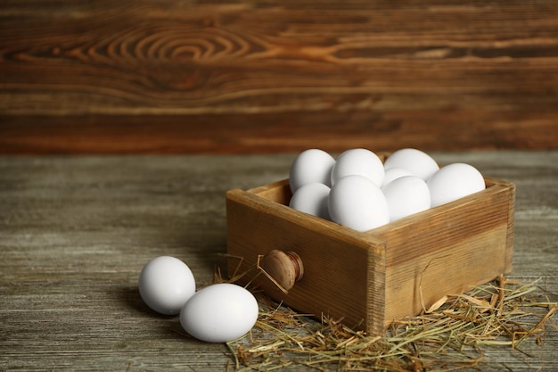 Raw eggs in drawer on wooden background