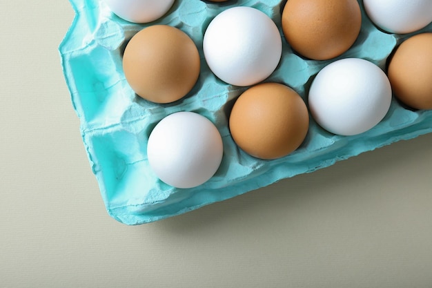 Raw eggs in package on light background