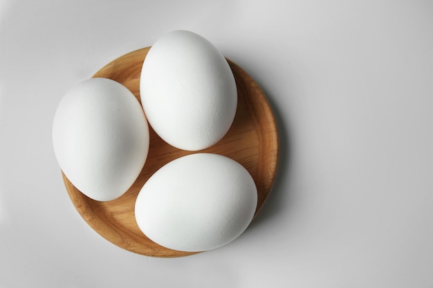 Raw eggs in plate on white background