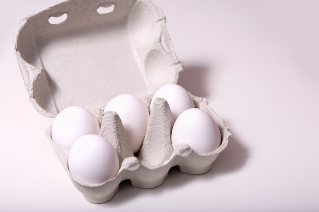 Raw eggs in recycled eco carton on light background