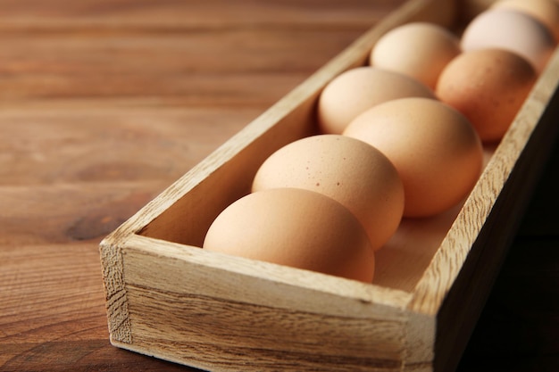Сырые яйца в деревянной коробке крупным планом