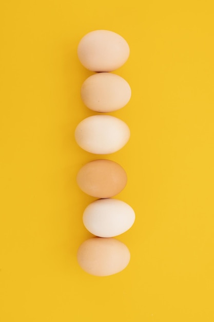 Raw eggs on yellow background