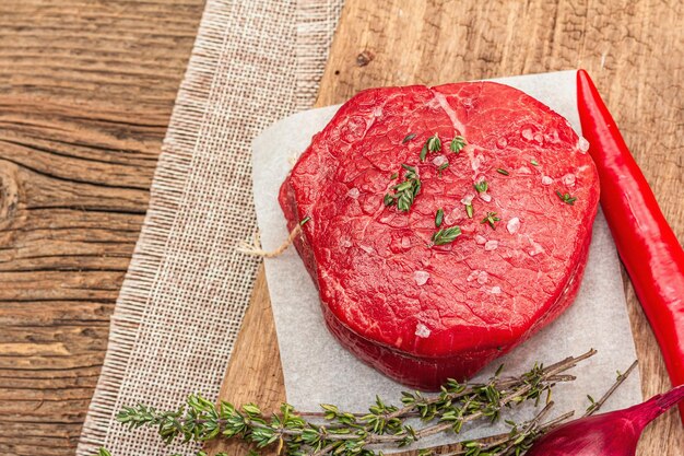 Raw Eye of round steak with spices and herbs on wooden background Fresh meat for cooking healthy food rustic style top view