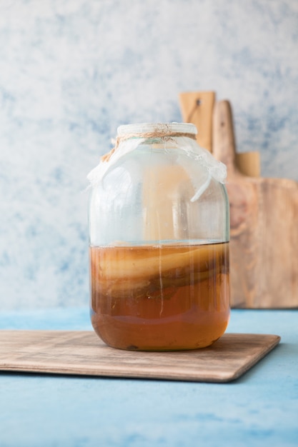 Foto superfood kombucha fatto in casa fermentato crudo alcolico o non alcolico. tè freddo con probiotico naturale sano in vetro con menta su sfondo blu