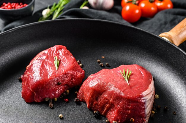 Photo raw filet mignon steak in a frying pan. beef tenderloin. black background. top view