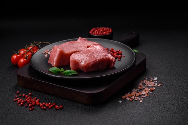 Raw fillet steak mignon beef with salt spices and herbs on a dark concrete background