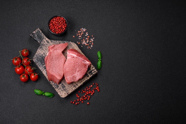Raw fillet steak mignon beef with salt spices and herbs on a dark concrete background