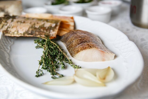 Photo raw fillet of zander in a plate, with ingredients for cooking