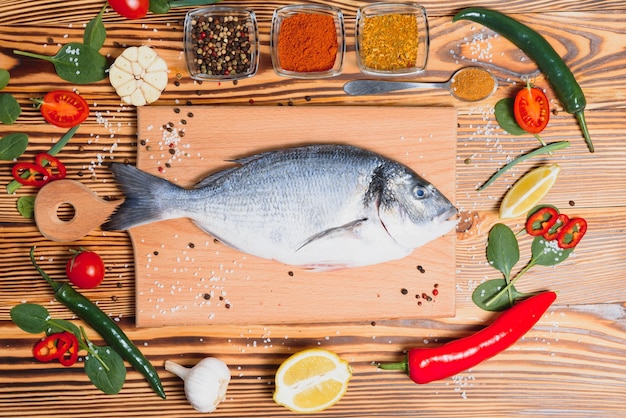 Raw fish cooking and ingredients. Dorado, lemon, herbs and spices. Top view with copy space on table