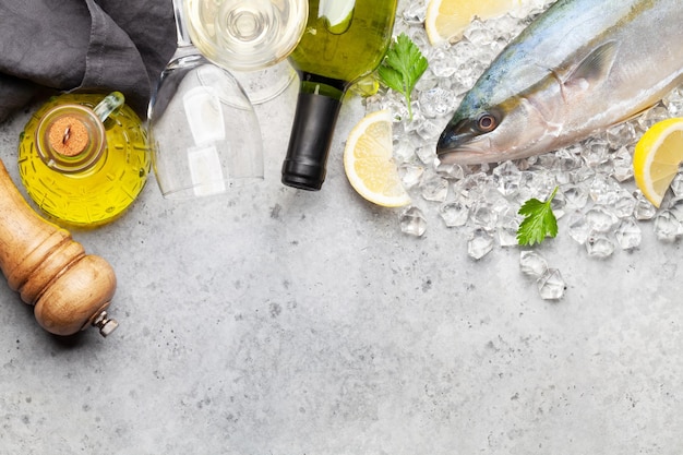 Raw fish cooking Seafood ingredients for dinner and white wine on stone table Top view flat lay with copy space