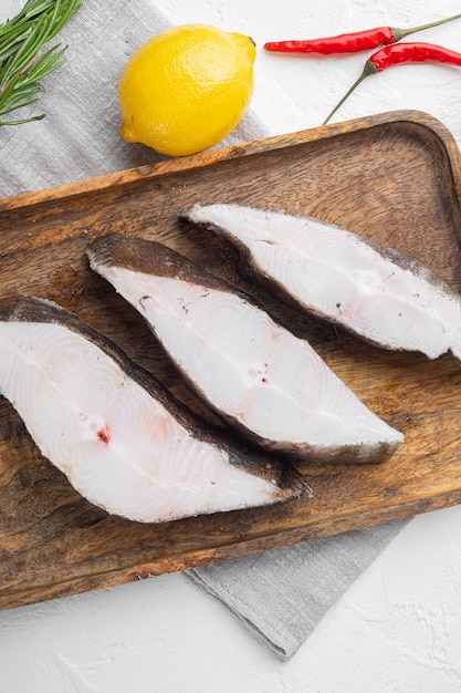 Raw fish cut set, with ingredients and rosemary herbs, on white stone table background, top view flat lay