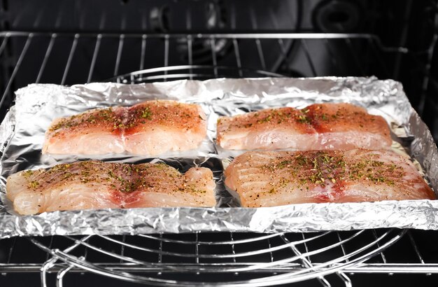 Raw fish fillets with spices in oven