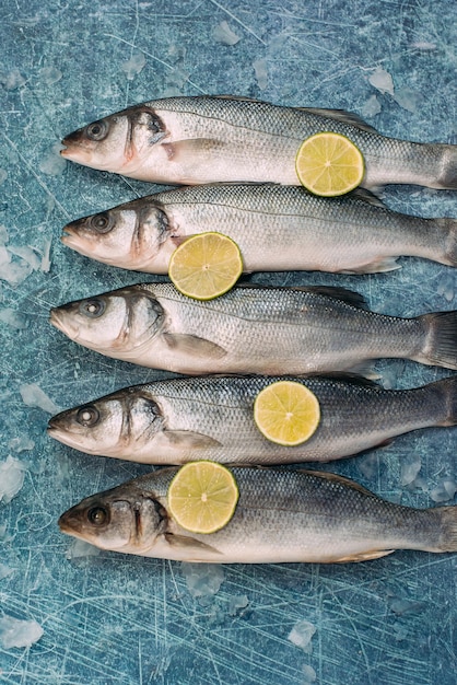 写真 スライスしたライムと青の背景に生の魚