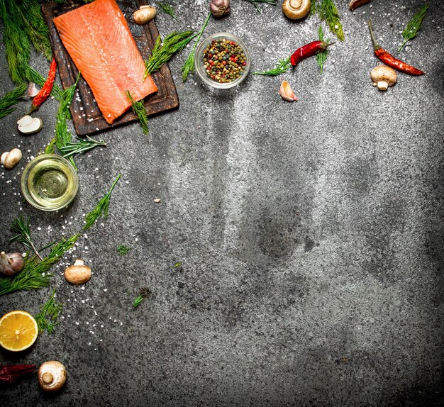 Raw fish. Salmon fillet with herbs and spices on rustic table.