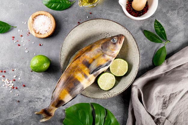 Raw fish sea bass or lingcod and seasonings for cooking it on a gray background top view